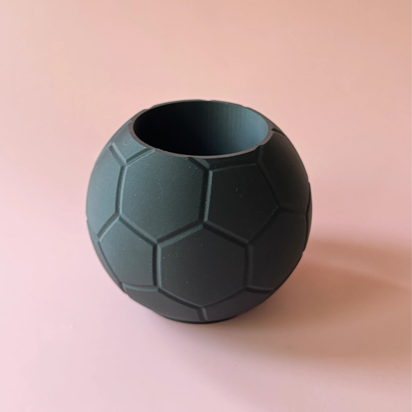 Schwarze Fussball Stiftebox vor rosa Hintergrund