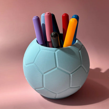 Hellblauer Fussball Stiftehalter vor rosa Hintergrund