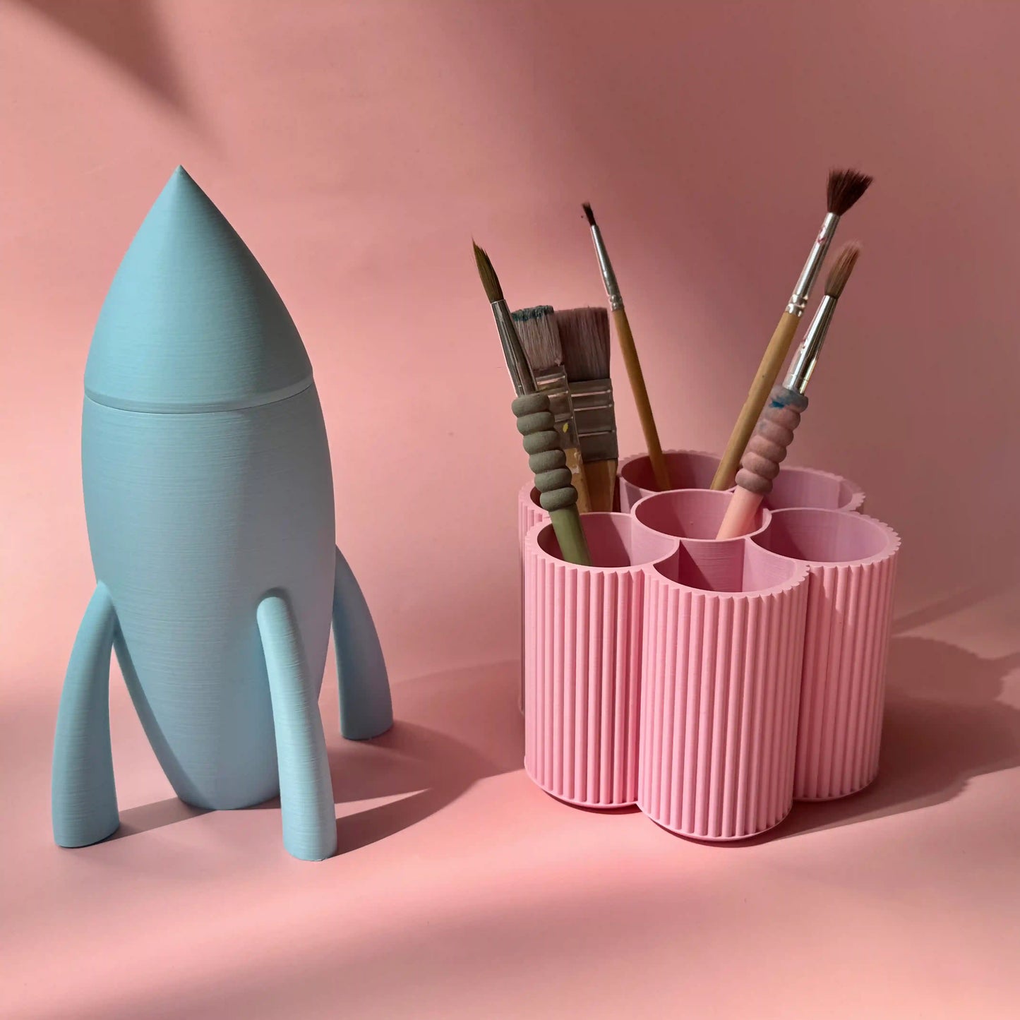 Stifteboxen Rakete in hellblau und Blume in rosa von tryk.design vor rosa Hintergrund
